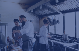 Chefs working together during service in a commercial kitchen, back of house.
