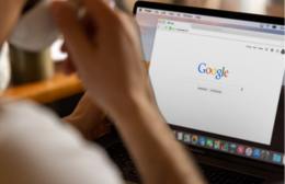 Person sitting at a laptop with the Google search homepage open on screen