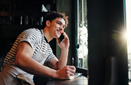 Chef laughing on the phone while jotting down an order, capturing the personal supplier relationship the article is about